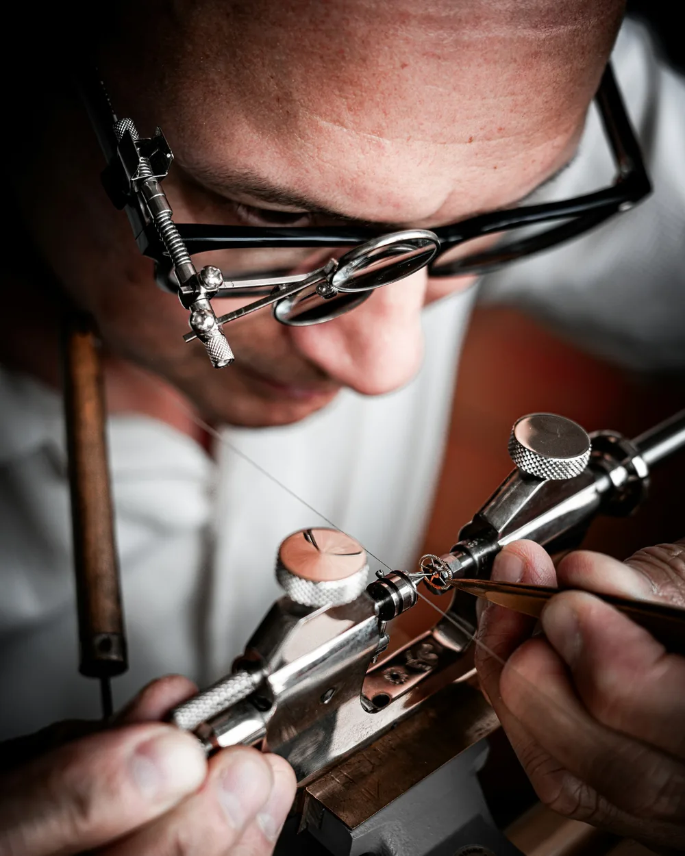Watchmaker adjusting a gear with tweezers on a workshop tool